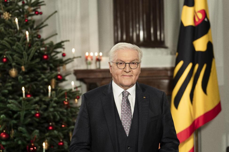 Bundespräsident Steinmeier steht vor einem festlich leuchtenden Weihnachtsbaum (links) und der Standarte (rechts) und hält seine Weihnachtsansprache